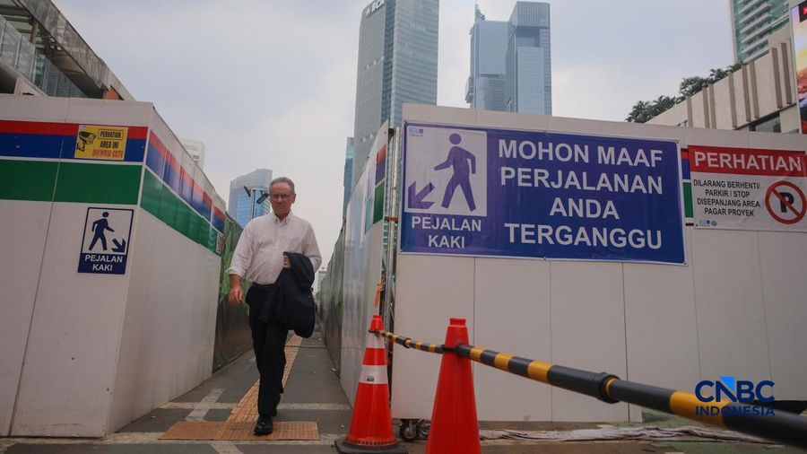 Warga melangkah kaki melewati trotoar darurat nan didekorasi menyerupai lorong taman labirin di atas area proyek pengembangan area Stasiun MRT Bundaran Hotel Indonesia, Jakarta, Rabu (24/6/2026).