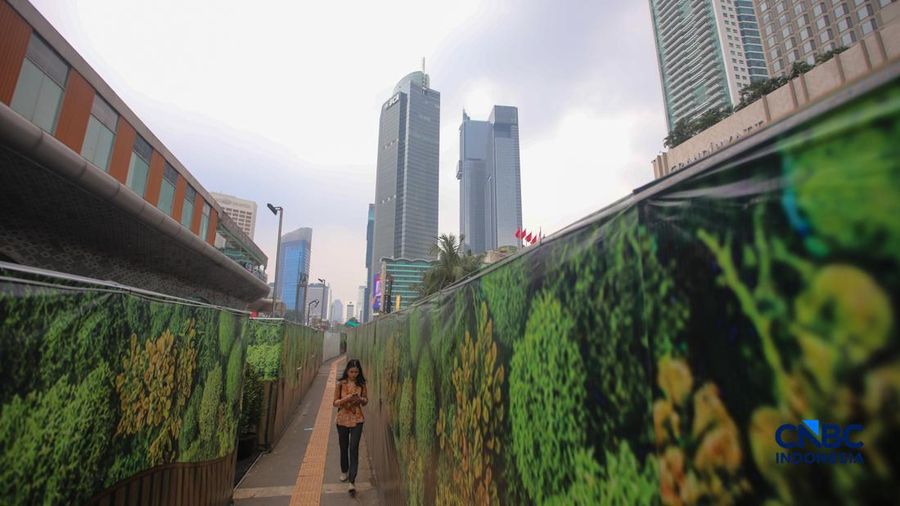 Warga melangkah kaki melewati trotoar darurat nan didekorasi menyerupai lorong taman labirin di atas area proyek pengembangan area Stasiun MRT Bundaran Hotel Indonesia, Jakarta, Rabu (24/6/2026).