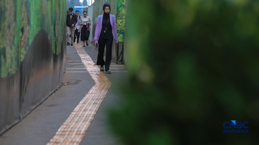 Warga melangkah kaki melewati trotoar darurat nan didekorasi menyerupai lorong taman labirin di atas area proyek pengembangan area Stasiun MRT Bundaran Hotel Indonesia, Jakarta, Rabu (24/6/2026).
