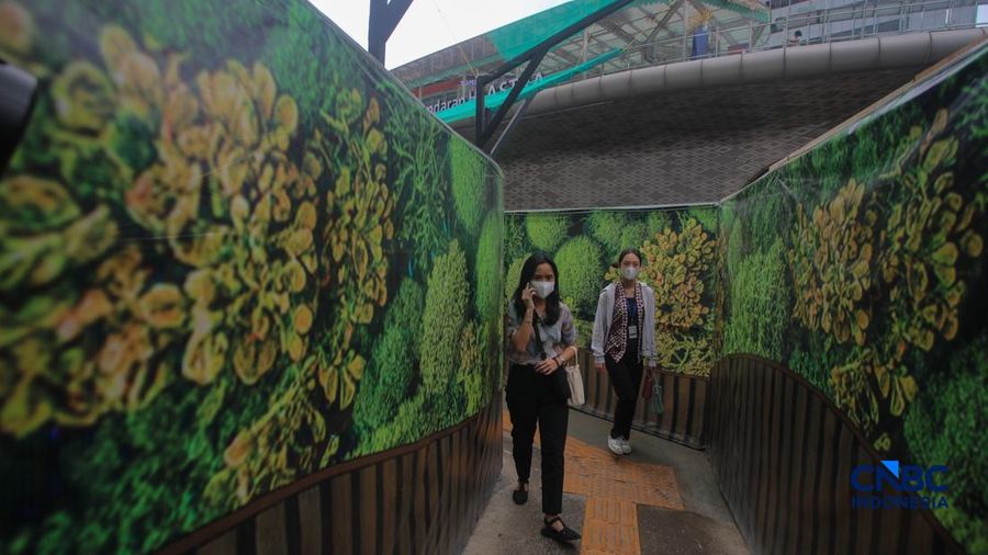 Warga melangkah kaki melewati trotoar darurat nan didekorasi menyerupai lorong taman labirin di atas area proyek pengembangan area Stasiun MRT Bundaran Hotel Indonesia, Jakarta, Rabu (24/6/2026).