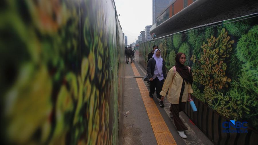 Warga melangkah kaki melewati trotoar darurat nan didekorasi menyerupai lorong taman labirin di atas area proyek pengembangan area Stasiun MRT Bundaran Hotel Indonesia, Jakarta, Rabu (24/6/2026).