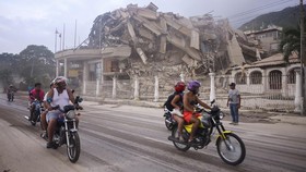 People ride past a collapsed building after an earthquake, in La Guaira, Venezuela, June 24, 2026. REUTERS/Maxwell Briceno     TPX IMAGES OF THE DAY