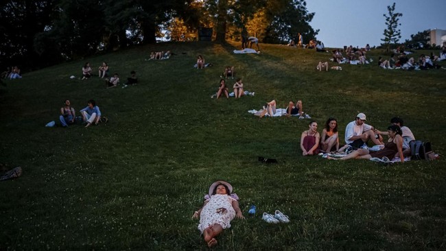 People sit on the grass to shelter from the heat in the Parc des Buttes-Chaumont in Paris, late June 25, 2026, as France experiences a heatwave. Hundreds of Parisians seeking relief from the heat took refuge in the Parc des Buttes-Chaumont, in the no