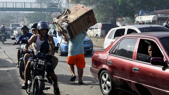 A man carries a washing machine that was looted, according to a Reuters witness, in the aftermath of earthquakes, in La Guaira, Venezuela, June 25, 2026. REUTERS/Maxwell Briceno
