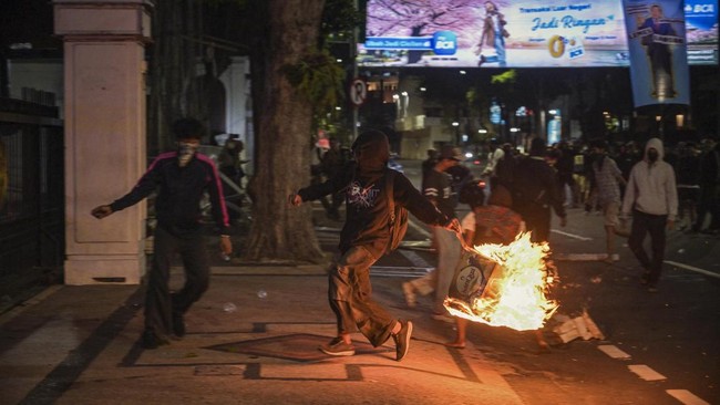 A student throws a fire box at riot police during protest against a rise in non-subsidised fuel prices, inefficient government spending and military involvement in civilian affairs and the government's free school meals programme (MBG) in Surabaya on