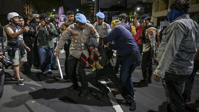 Indonesian police arrest a student following clashes during protest against a rise in non-subsidised fuel prices, inefficient government spending and military involvement in civilian affairs and the government's free school meals programme (MBG) in S