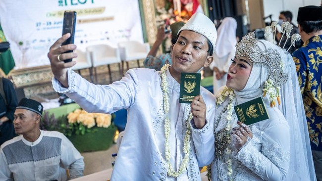 Pasangan pengantin menunjukkan buku nikah usai prosesi nikah massal pada Nikah Fest 2026 di Jakarta, Sabtu (27/6/2026). Kementerian Agama (Kemenag) menggelar program nikah massal yang diikuti 30 pasangan dari berbagai daerah di Indonesia sebagai upay