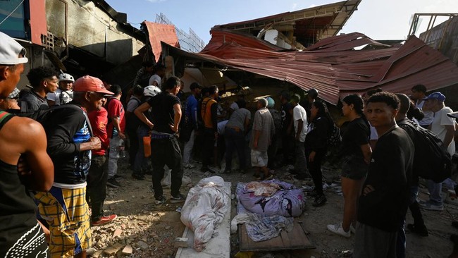 People gather around the body of a casualty, amid the rubble-debris of damaged buildings in the aftermath of earthquakes in Venezuela, June 25, 2026.