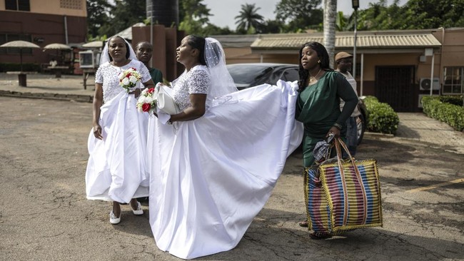 Twin sisters Taiwo and Kehinde Adediran wait for their car on the parking lot ahead of their wedding ceremony with twin brothers Taiwo and Kehinde Oguntoye in University of Ibadan Hotels on June 20, 2026. Two brides in identical white dresses. Two gr