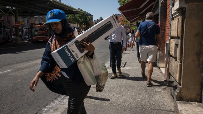 A woman carries a fan as she walks on street during a heatwave in Toulouse on June 23, 2026. (Photo by Ed JONES / AFP)