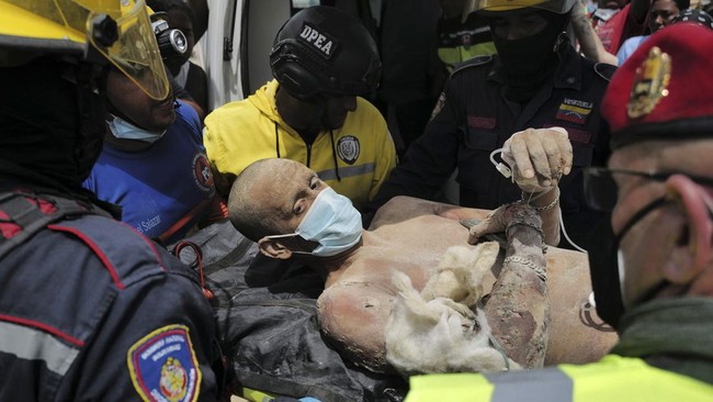 Rescuers load a person onto an ambulance after being pulled alive from the rubble of a collapsed building in Caraballeda, La Guaira state, Venezuela, on June 28, 2026, following earthquakes. Thousands of rescuers, relatives and volunteers dig day and