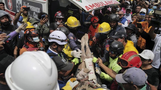 Rescuers carry a person after being pulled alive from the rubble of a collapsed building in Caraballeda, La Guaira state, Venezuela, on June 28, 2026, following earthquakes. Thousands of rescuers, relatives and volunteers dig day and night through mo