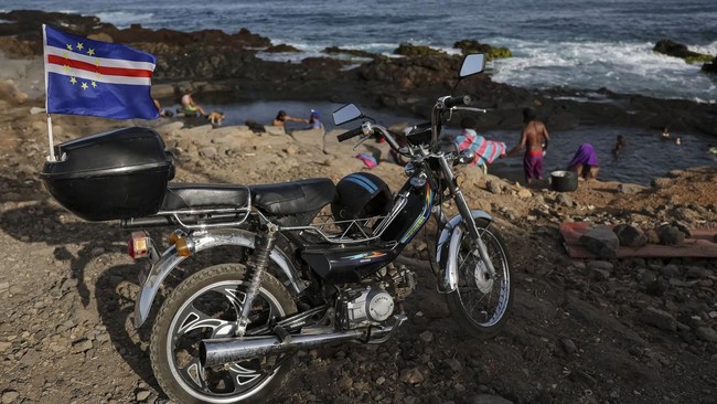 The Cape Verdean flag flutters on a motorcycle as people relax at the shore at Kebra Kanela in Gamboa, Praia, Cape Verde, June 28, 2026. REUTERS/Sodiq Adelakun