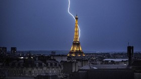 Lightning strikes during a storm near The Eiffel Tower in Paris late June 13, 2025. (Photo by Martin BUREAU / AFP)