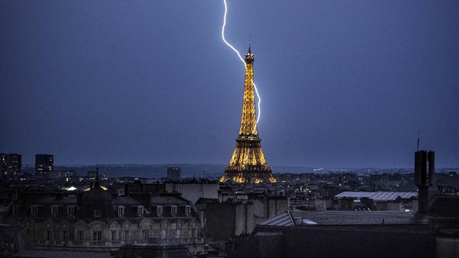Lightning strikes during a storm near The Eiffel Tower in Paris late June 13, 2025. (Photo by Martin BUREAU / AFP)
