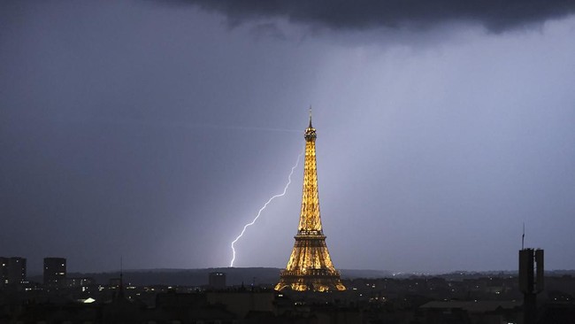 Lightning strikes during a storm near The Eiffel Tower in Paris late June 13, 2025. (Photo by Martin BUREAU / AFP)