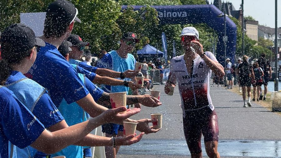 Para sukarelawan menawarkan minuman kepada seorang atlet Ironman selama gelombang panas nan sedang berjalan di Frankfurt, Jerman, 28 Juni 2026.