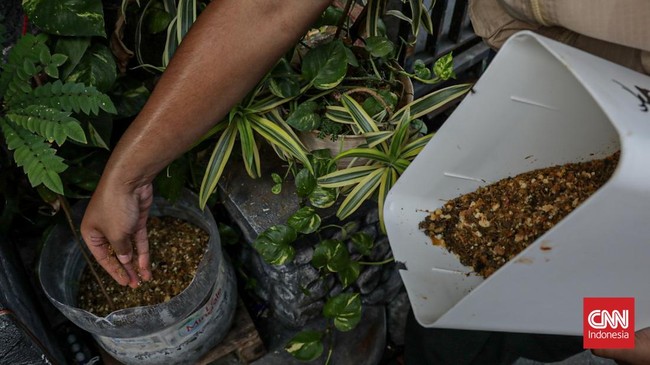 Warga menuangkan sampah sisa makanan ke dalam gerobak Komling untuk diolah menjadi kompos di Gandaria Utara, Kebayoran Baru, Jakarta, Senin (29/6). (CNN Indonesia/Febria Adha L).
