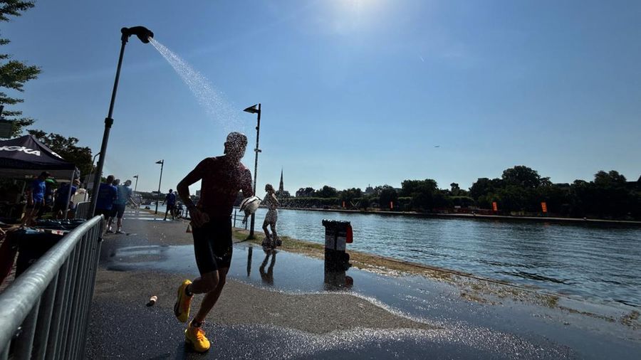 Seorang atlet Ironman berlari melewati pancuran di dekat Sungai Main untuk mendinginkan diri selama gelombang panas nan sedang berjalan di Frankfurt, Jerman, 28 Juni 2026.