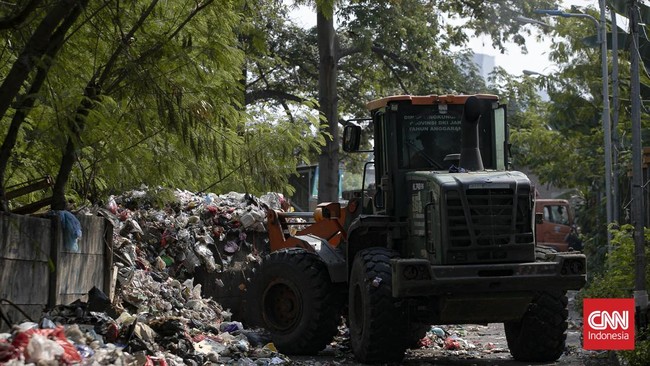 Petugas melakukan pembersihan tumpukan sampah rumah tangga yang menutupi sebagian akses Jalan Gang Swadaya, Kelurahan Cakung Barat, Kecamatan Cakung, Jakarta Timur. Kondisi tersebut mengganggu aktivitas warga di sekitar Rusun Albo akibat bau menyenga