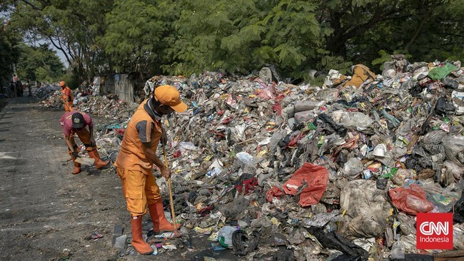 Petugas melakukan pembersihan tumpukan sampah rumah tangga yang menutupi sebagian akses Jalan Gang Swadaya, Kelurahan Cakung Barat, Kecamatan Cakung, Jakarta Timur. Kondisi tersebut mengganggu aktivitas warga di sekitar Rusun Albo akibat bau menyenga