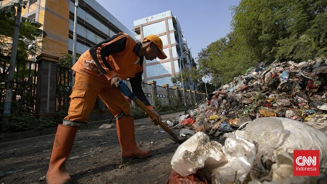Petugas melakukan pembersihan tumpukan sampah rumah tangga yang menutupi sebagian akses Jalan Gang Swadaya, Kelurahan Cakung Barat, Kecamatan Cakung, Jakarta Timur. Kondisi tersebut mengganggu aktivitas warga di sekitar Rusun Albo akibat bau menyenga