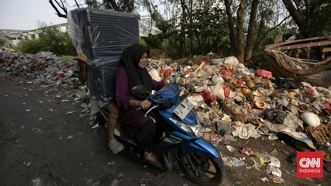 Petugas melakukan pembersihan tumpukan sampah rumah tangga yang menutupi sebagian akses Jalan Gang Swadaya, Kelurahan Cakung Barat, Kecamatan Cakung, Jakarta Timur. Kondisi tersebut mengganggu aktivitas warga di sekitar Rusun Albo akibat bau menyenga