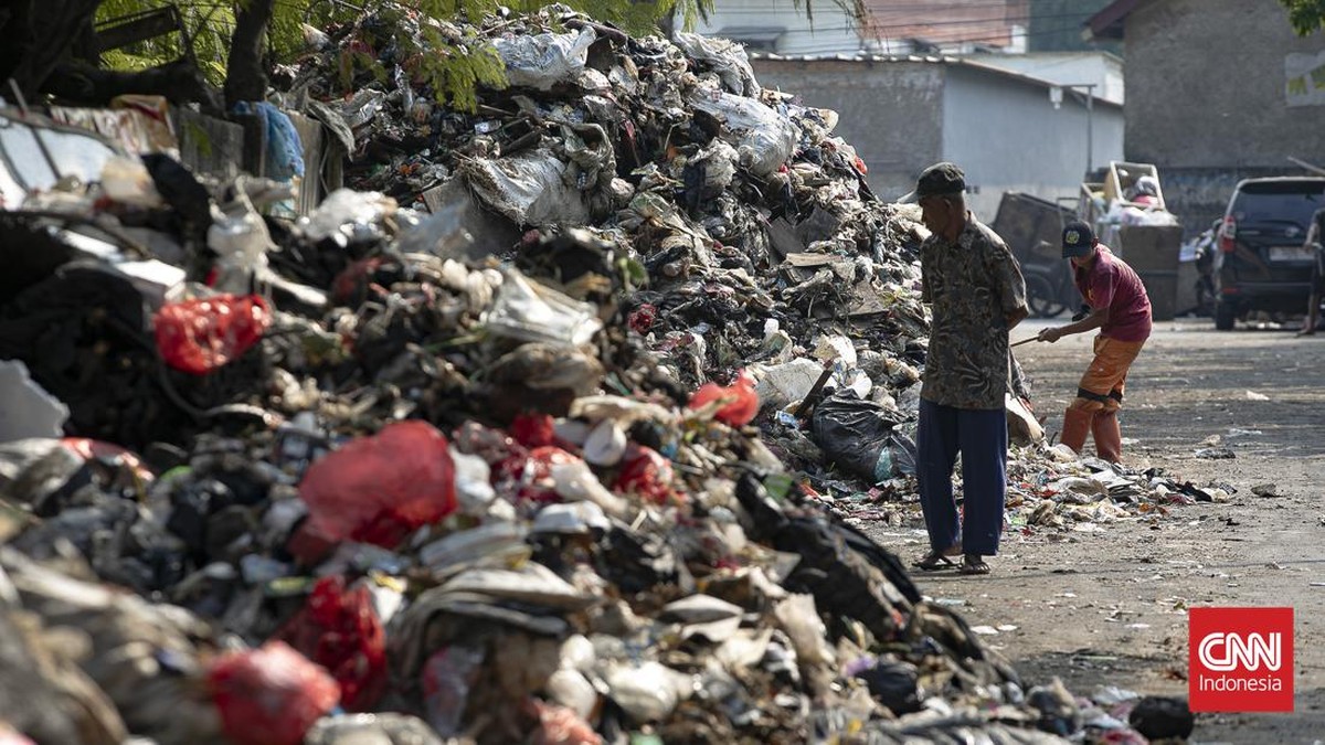 Petugas melakukan pembersihan tumpukan sampah rumah tangga yang menutupi sebagian akses Jalan Gang Swadaya, Kelurahan Cakung Barat, Kecamatan Cakung, Jakarta Timur. Kondisi tersebut mengganggu aktivitas warga di sekitar Rusun Albo akibat bau menyenga