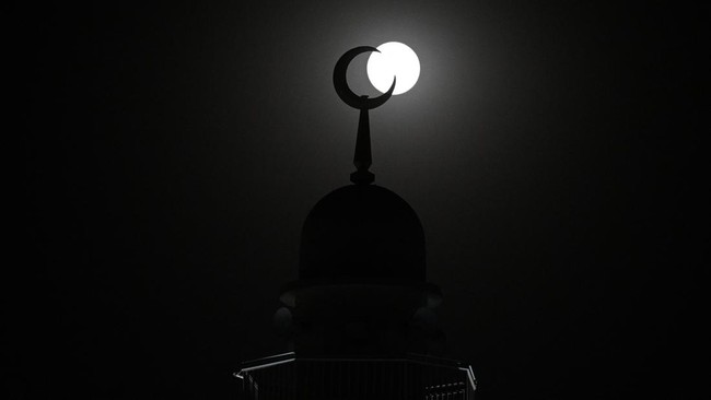 Bulan Stroberi terbit di balik sebuah menara masjid di Kota Kuwait pada tanggal 29 Juni 2026. (Foto: YASSER AL-ZAYYAT / AFP)