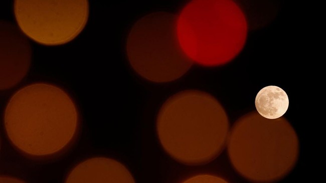 Strawberry Moon terlihat melalui instalasi lampu hias di Doha pada 29 Juni 2026. (Foto: Karim JAAFAR / AFP)