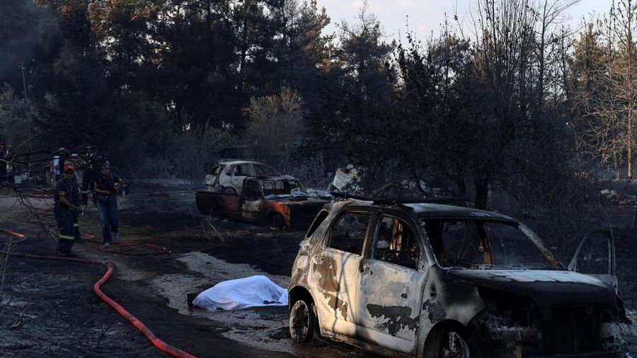 Jenazah korban kebakaran rimba tergeletak tertutup kain di samping mobil nan terbakar setelah kebakaran rimba di dekat desa Liti, Thessaloniki, Yunani, 30 Juni 2026. (REUTERS/Alexandros Avramidis)