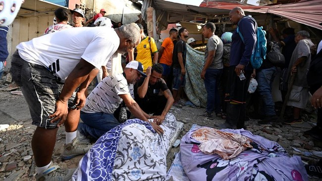 People mourn next to the body of a casualty, amid the rubble and debris of damaged buildings in the aftermath of earthquakes in La Guaira, Venezuela, June 25, 2026. REUTERS/Maxwell Briceno