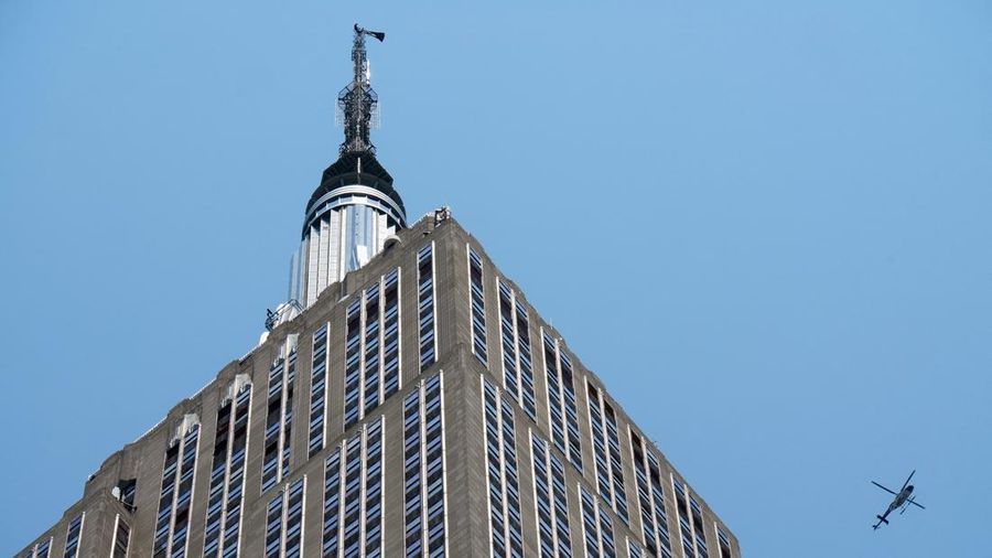 Dua orang membentangkan spanduk di puncak Gedung Empire State di distrik Manhattan, New York, AS, Rabu (1/7/2026). (REUTERS/Adam Gray)