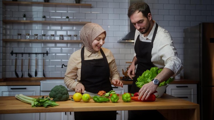 Young married couple enjoy conversation in the modern kitchen and prepare healthy vegetarian food preparation together