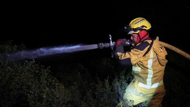 A firefighter sprays water as a wildfire burns in Pouzols-Minervois near Narbonne, France, July 3, 2026. REUTERS/Alexandre Dimou