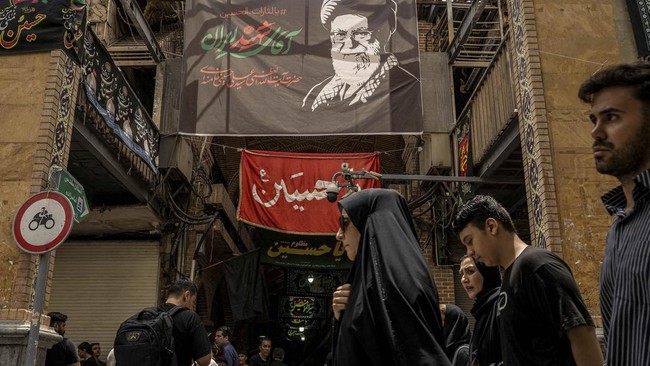 People walk in a market under a banner depicting Iran's late Supreme Leader Ayatollah Ali Khamenei, ahead of his farewell ceremony, in Tehran, Iran, July 2, 2026. REUTERS/Alkis Konstantinidis   Foreign media in Iran operate under guidelines set by th