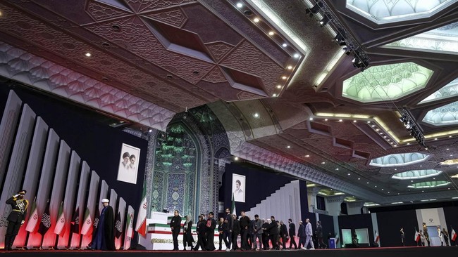 People walk past the coffins of Iran's late Supreme Leader Ayatollah Ali Khamenei and his family members, on the day international delegates participate in a farewell ceremony for Khamenei, who was killed on February 28 during Israeli and U.S. airstr