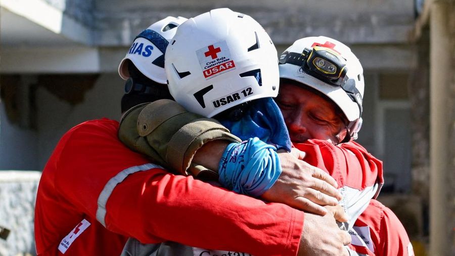 Para petugas penyelamat saling berpelukan setelah menarik keluar korban selamat Hernan Alberto Gil, nan terjebak selama lebih dari seminggu setelah gempa bumi 24 Juni, dari reruntuhan pusat perbelanjaan di La Guaira, Venezuela, 2 Juli 2026.