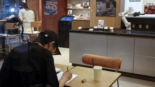 People sit inside an unmanned cafe where a robot arm prepares coffee in Seoul, South Korea, June 19, 2026. REUTERS/Kim Soo-hyeon
