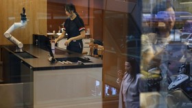 A customer gets coffee prepared by a robot arm at an unmanned cafe in Seoul, South Korea, June 19, 2026. REUTERS/Kim Soo-hyeon