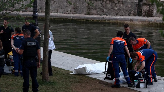 Emergency services gather around a body bag containing a deceased person, at the scene where a person drowned in the Canal Saint-Martin after public swimming was permitted in certain areas due to high temperatures amid a heatwave in Paris, France, Ju