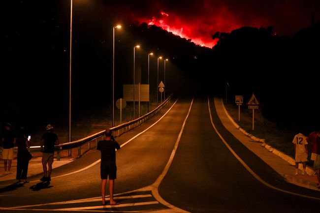 EUROPE-WEATHER/SPAIN-WILDFIRE People look on as flames and smoke from a wildfire rise near Calonge, Spain, July 4, 2026. REUTERS/Bruna Casas TPX IMAGES OF THE DAY