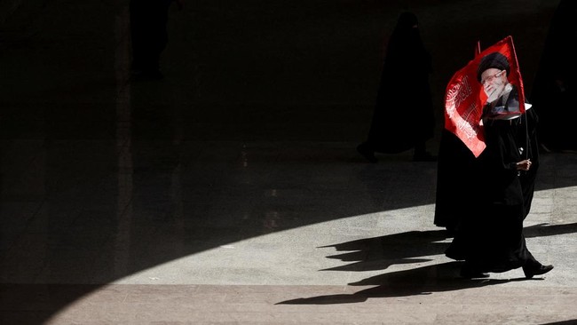 Mourners with flags walk at the Imam Khomeini Grand Mosalla, as people gather on the day of a public farewell ceremony to pay their respects to late Supreme Leader Ayatollah Ali Khamenei, who was killed on February 28 in Israeli and U.S. airstrikes,