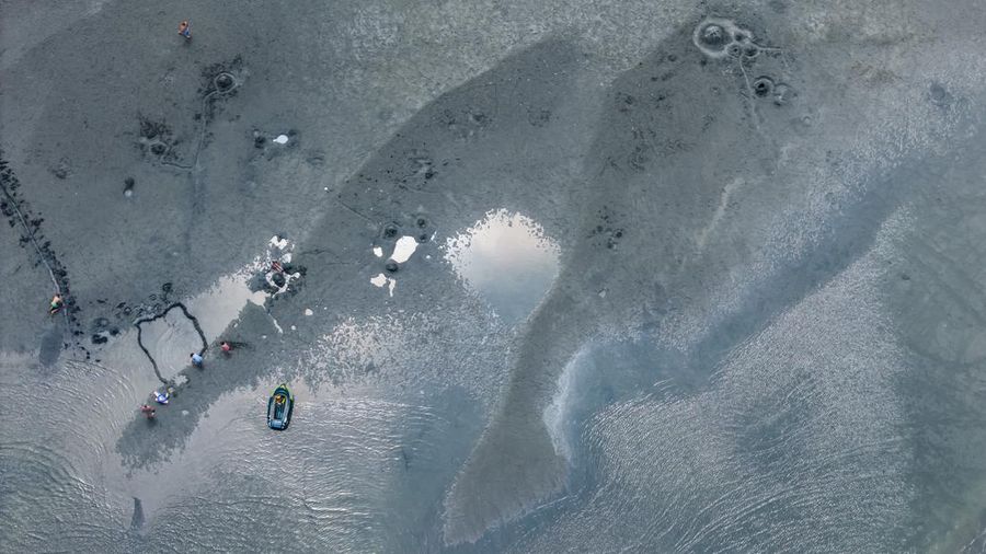A drone view shows people walking on an exposed sandbank locally known as