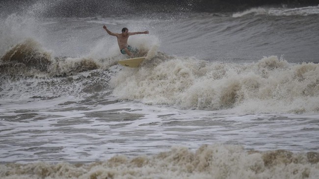 A surfer rides a high wave due to the effects of Super Typhoon Bavi in Guam on July 5, 2026. People in Guam and the Northern Marianas moved to emergency evacuation centers and made last-minute preparations on July 5, hours before a