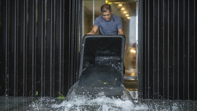 A hotel staff member removes water that leaked into a building during heavy rain brought by Super Typhoon Bavi in Guam on July 6, 2026. (Photo by Yuichi YAMAZAKI / AFP)