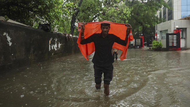 A man covers himself with a cloth as he wades through a flooded street after heavy rains in Mumbai, India, July 1, 2026. REUTERS/Francis Mascarenhas