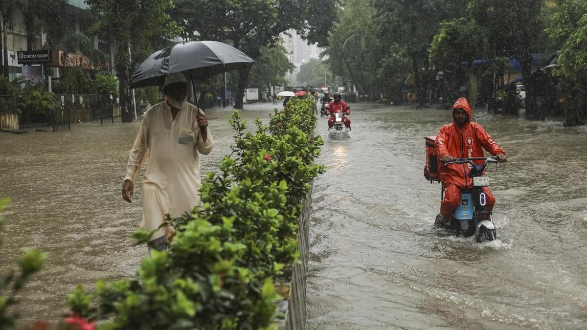 A man watches as gig workers ride through a waterlogged street after heavy rains in Mumbai, India, July 4, 2026. REUTERS/Francis Mascarenhas
