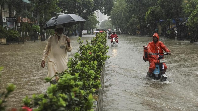 A man watches as gig workers ride through a waterlogged street after heavy rains in Mumbai, India, July 4, 2026. REUTERS/Francis Mascarenhas