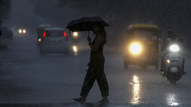 A woman carrying an umbrella crosses a road during heavy monsoon rain as vehicles drive through low visibility in Ahmedabad, India, July 6,2026. REUTERS/Amit Dave     TPX IMAGES OF THE DAY